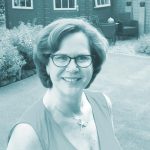 Frau in Sportbekleidung mit Schmuck, lachend.