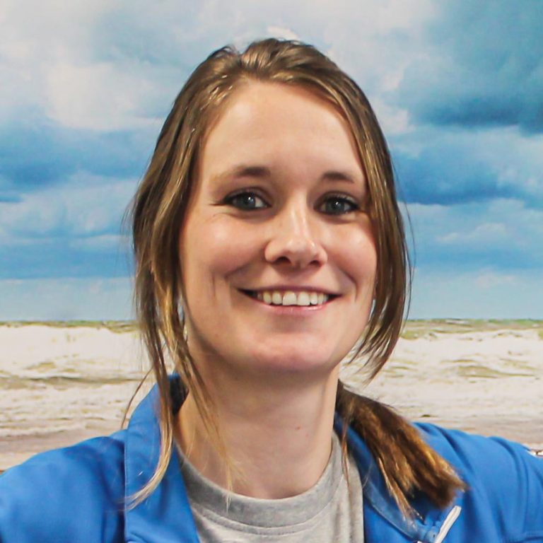 Frau mit blonden Haaren und blauem Jackett lächelt in die Kamera.