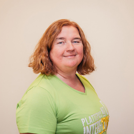 Frau in grünem T-Shirt, Fitness-Ernährungsberaterin, lächelt.