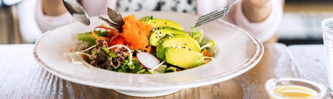 Person eating mindfully at a quiet table, focusing on the colors, textures and aromas of a simple balanced meal.