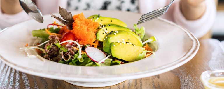 Person eating mindfully at a quiet table, focusing on the colors, textures and aromas of a simple balanced meal.