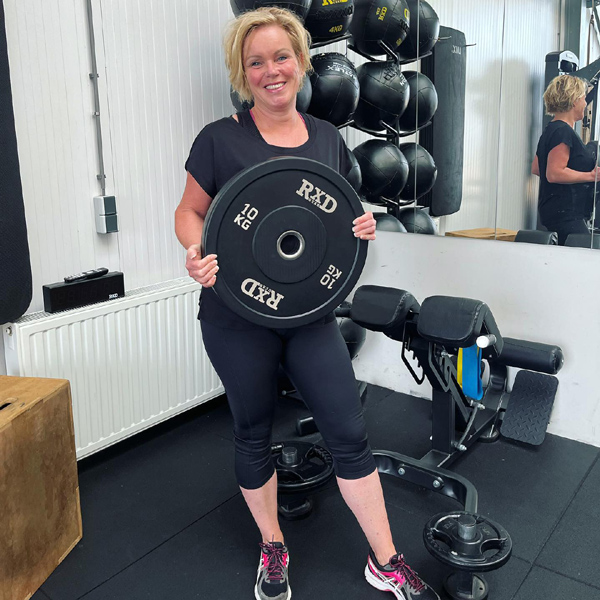 Frau mit Gewichtsscheibe im Fitnessstudio, bereit für ihr Training.